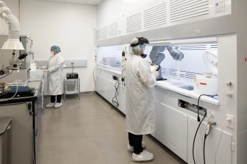 Two people standing in chemical lab overseeing silicon etching processing using acid dunk baths and spin coater